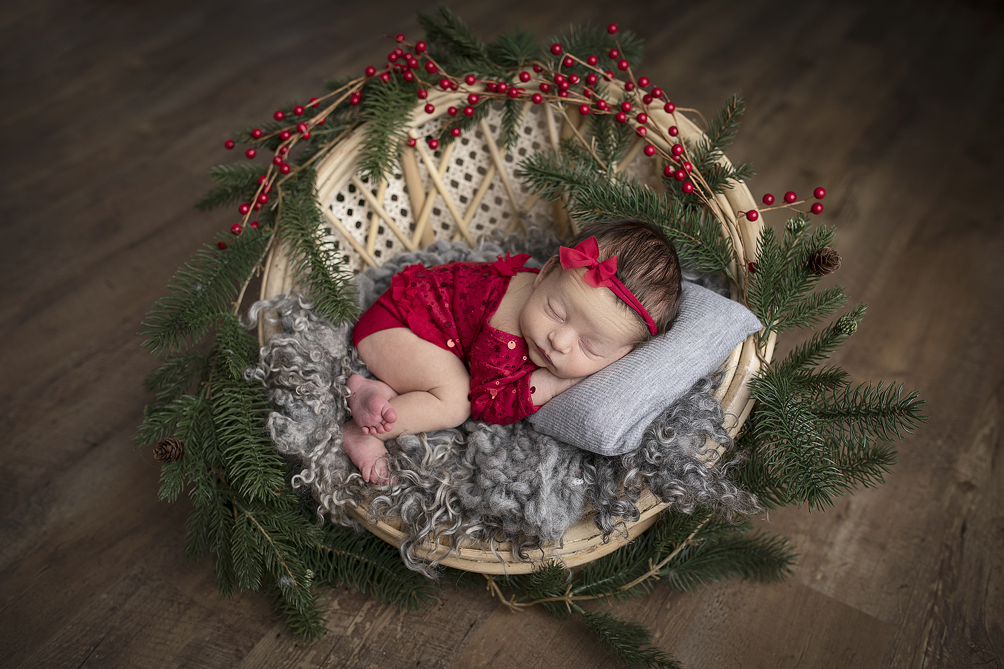 Newborn baby photo from newborn session. Baby is wearing red outfit and laying in a small round chair