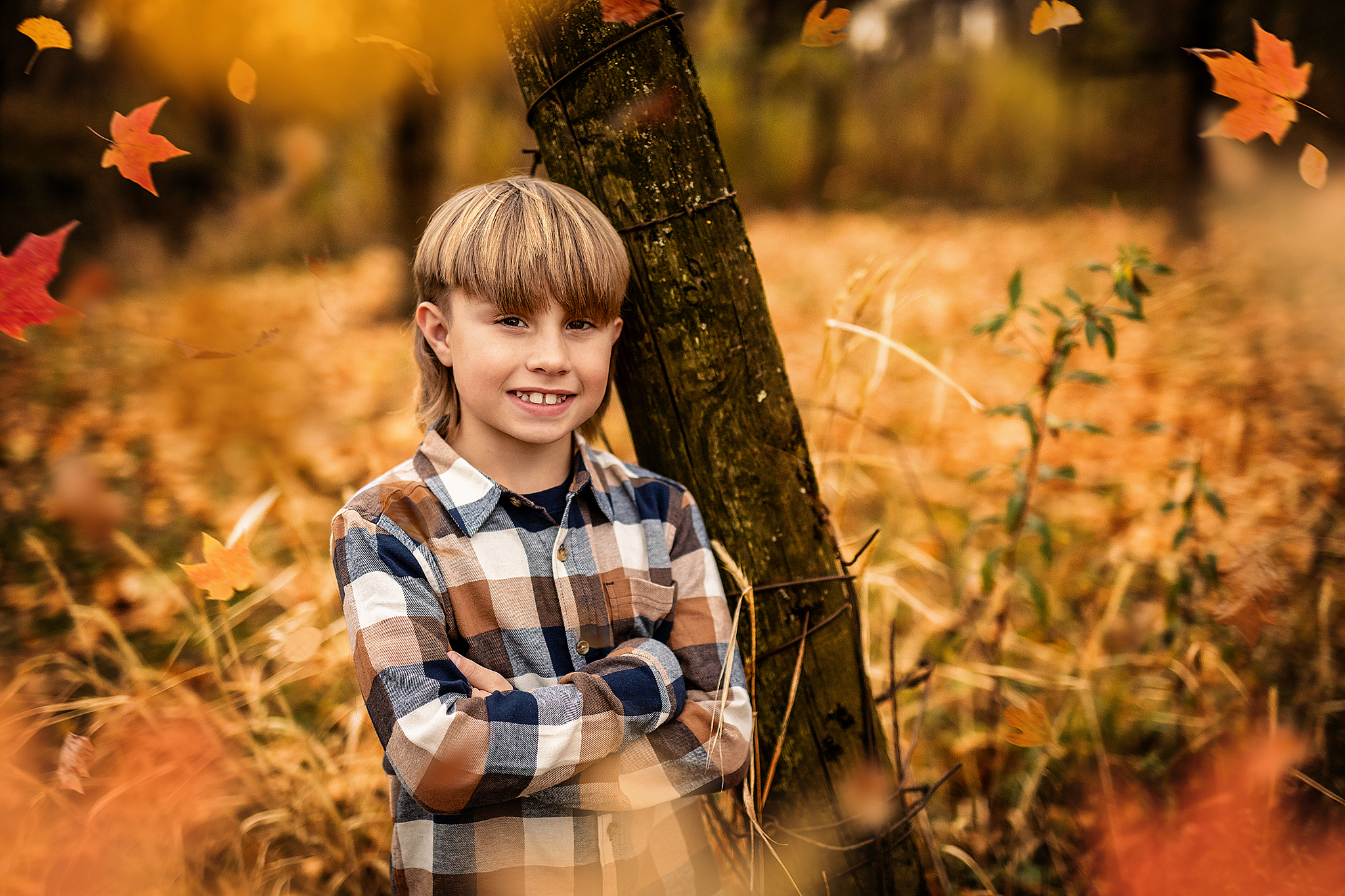 Young boy standing against pole in fall with cheeky smile for pediatric dentist in mansfield