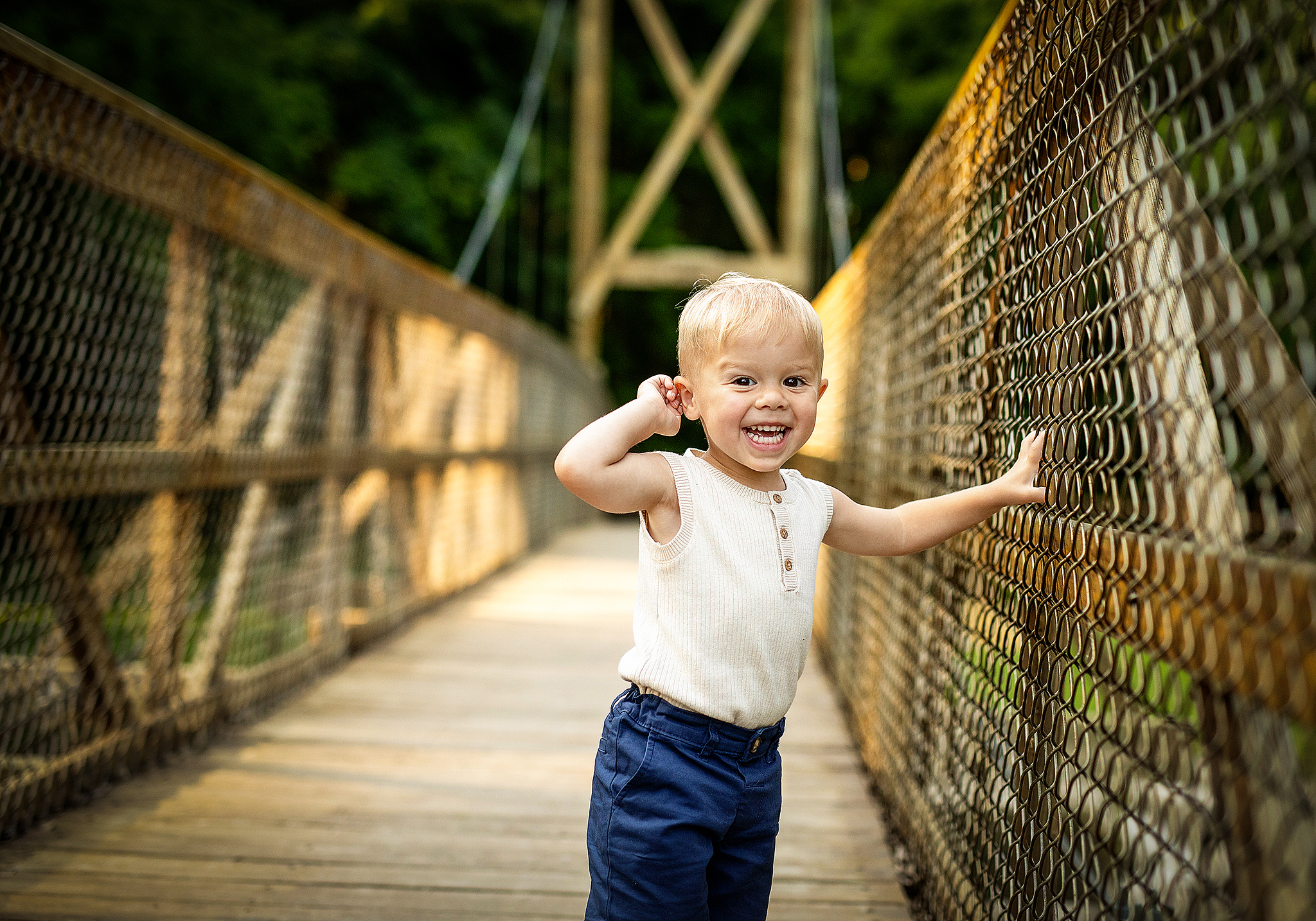 Little boy with ornery grin on his face standing on a bridge