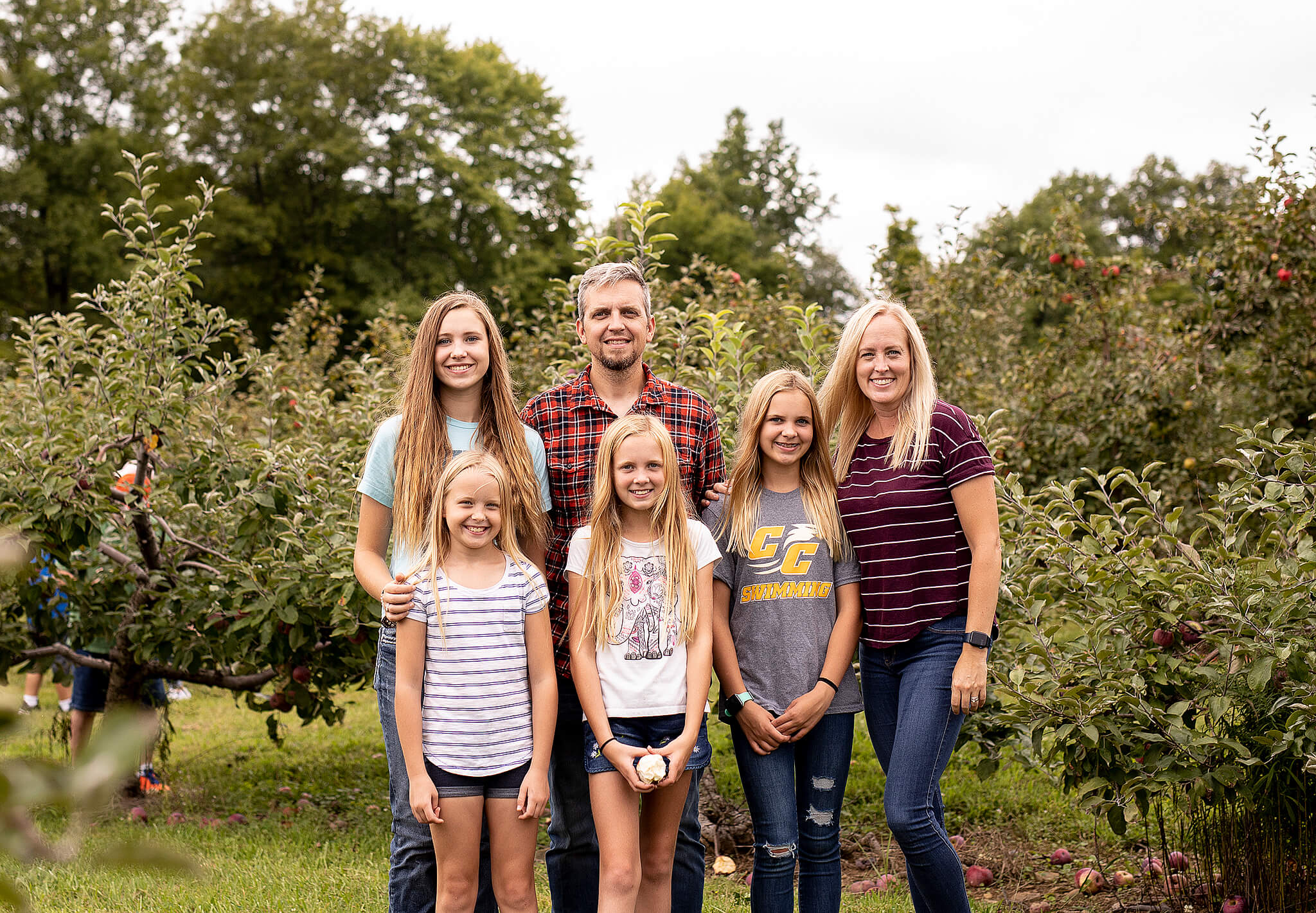 Family of 6 standing in front of an apple tree