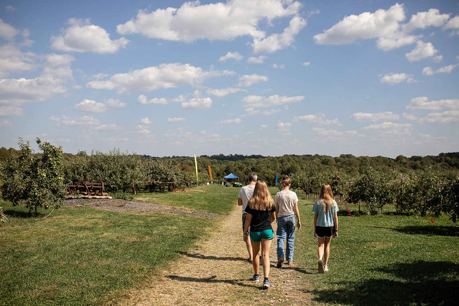 Family walking down a path at apple orchard for apple picking