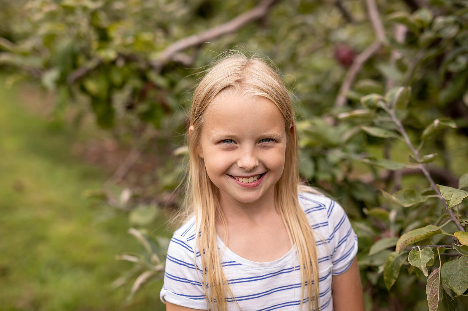 Young girl standing in front of an apple tree at apple hill orchard