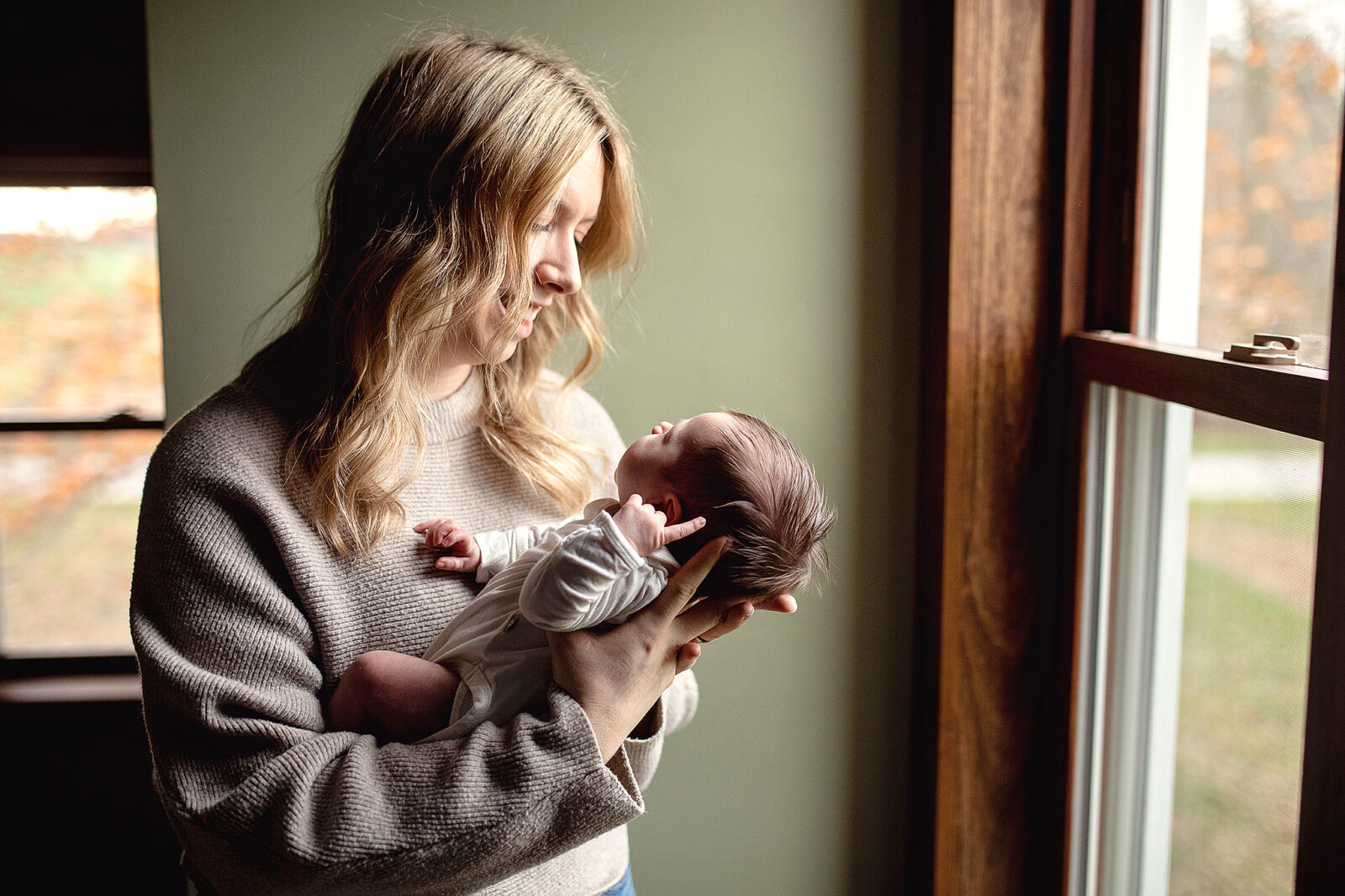 mom holding newborn baby in front of pretty window light