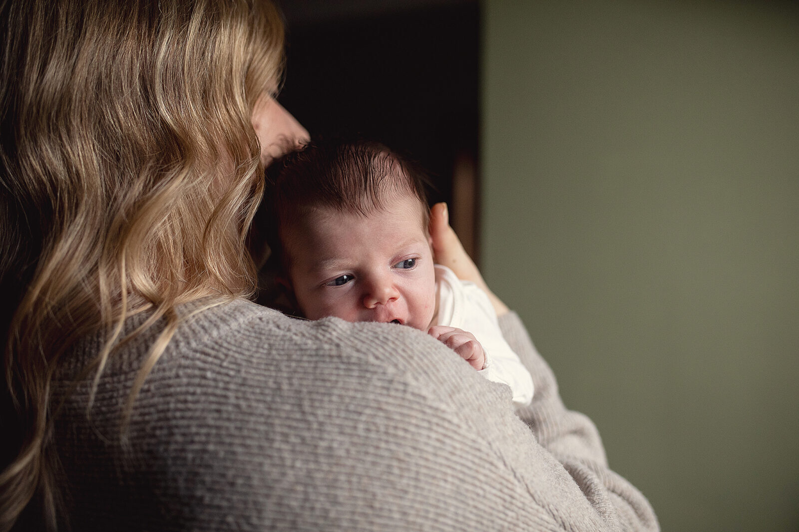 newborn baby in lifestyle session peeking over moms shoulder as mom holds her