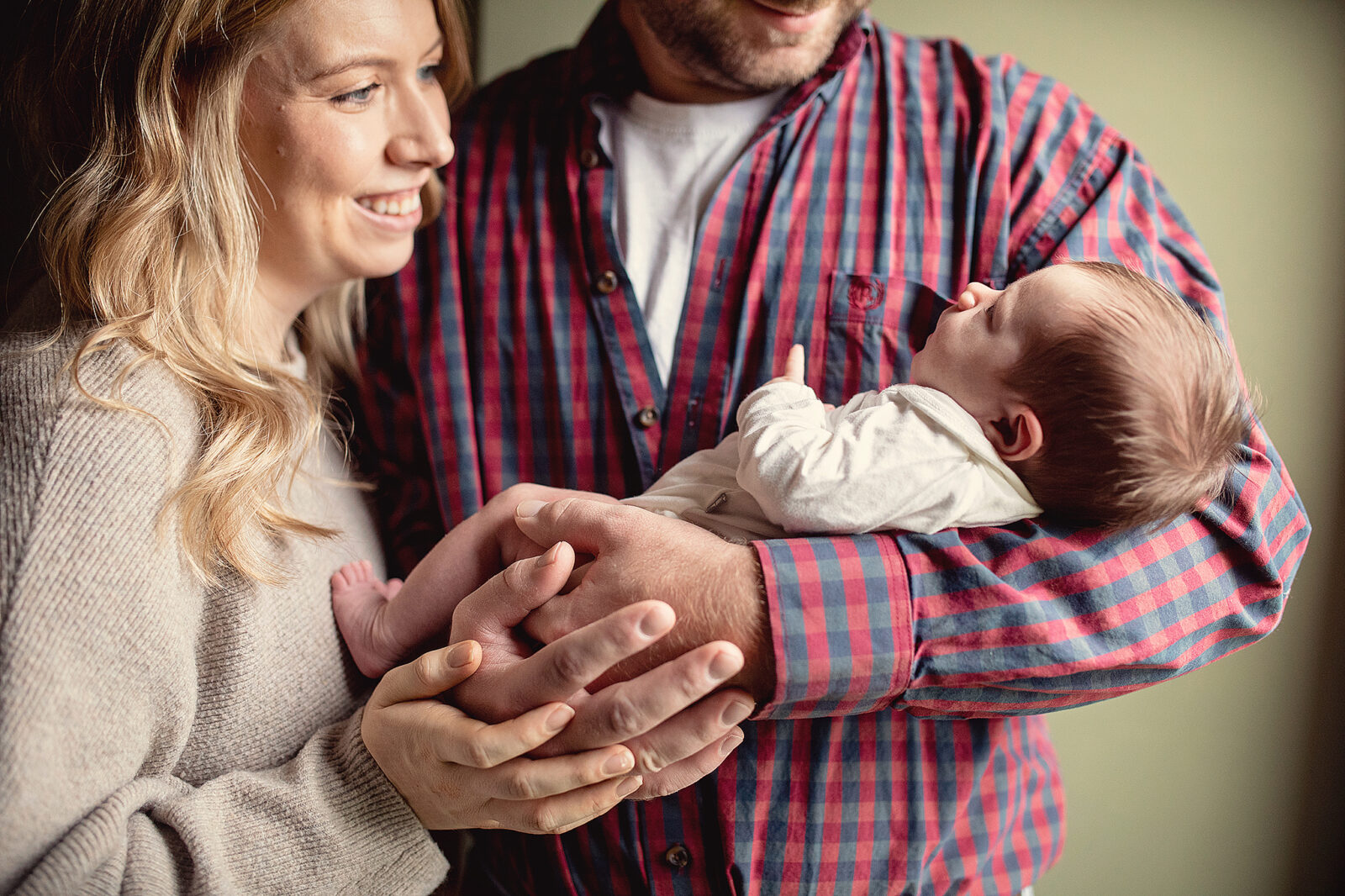 Dad holding newborn baby girl with mom cuddled in close