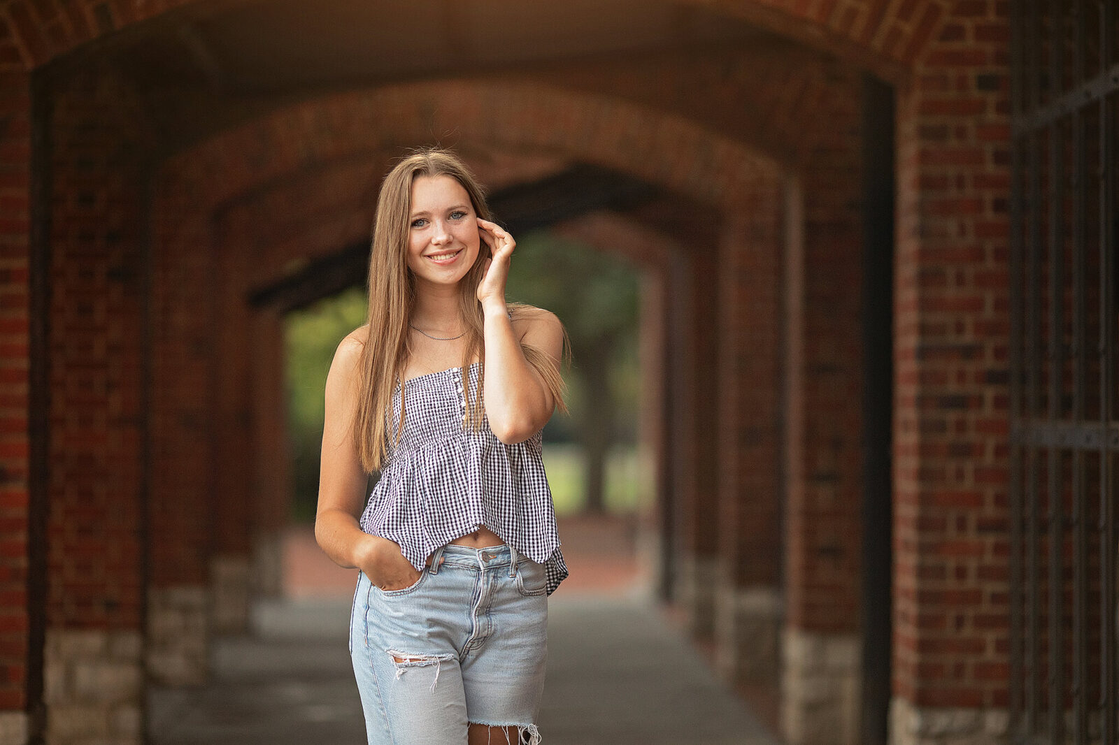 High school girl standing underneath brick arches at a scioto mile senior session
