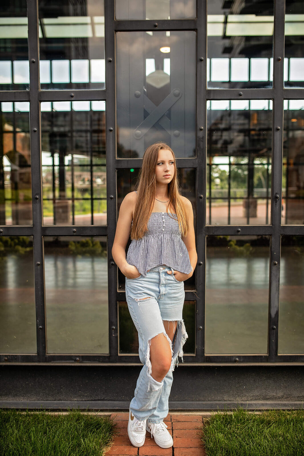 High school senior girl standing in front of a glass building